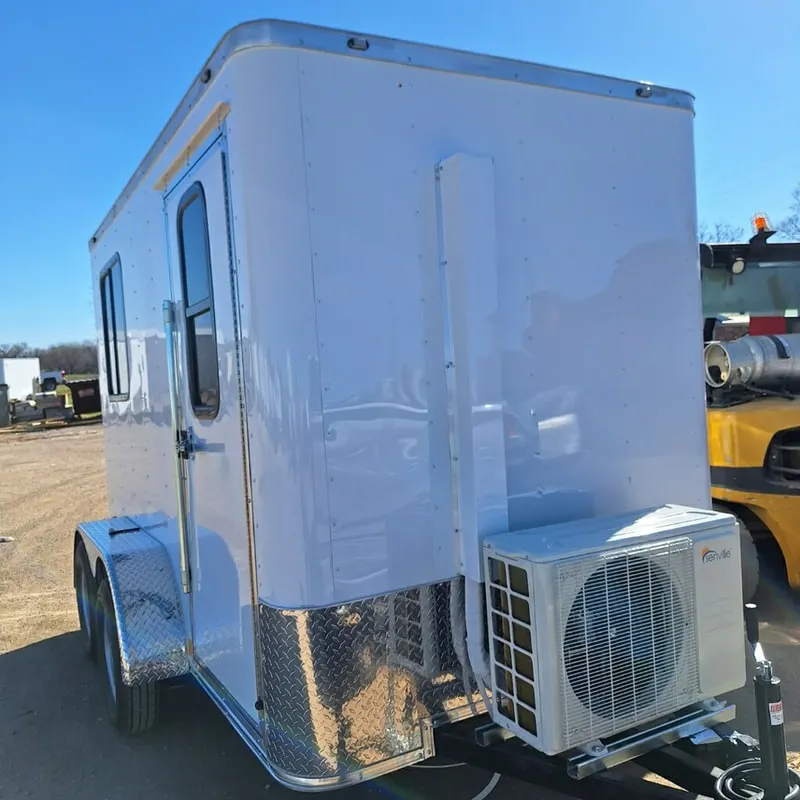 White tandem-axle mobile guard shack trailer with a wall-mounted mini-split A/C unit